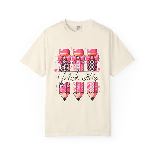 Beige t-shirt with pink pencils and bows design on a white background