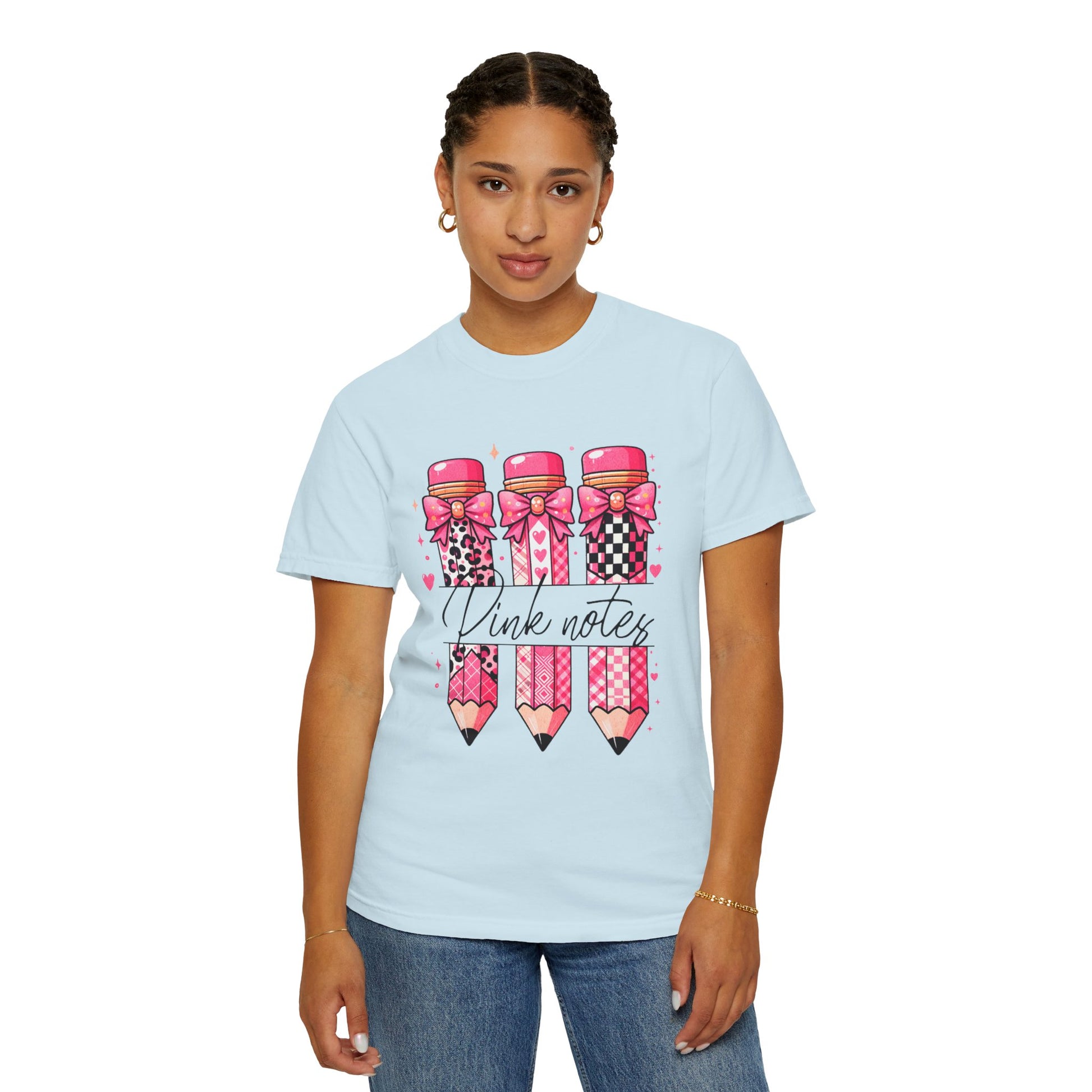 Person wearing a light blue t-shirt with pink and black pencil design and text.