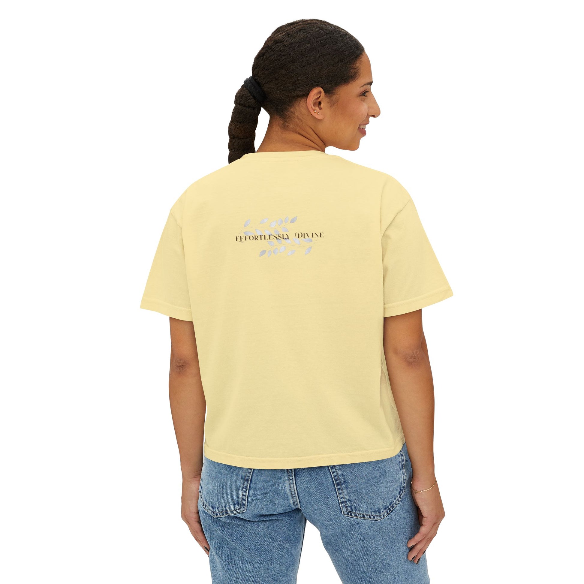 Woman wearing a butter t-shirt with text on the back, standing against a white background